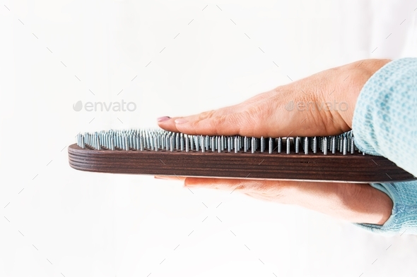 female hands holding a sadhu board for nail therapy on a white background. sharp nails