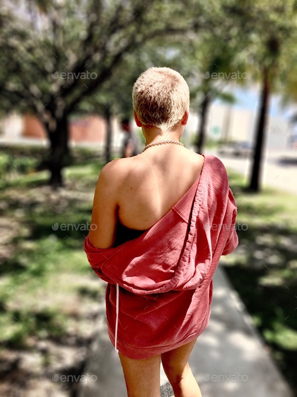 Woman standing in park with jacket hanging off shoulder
