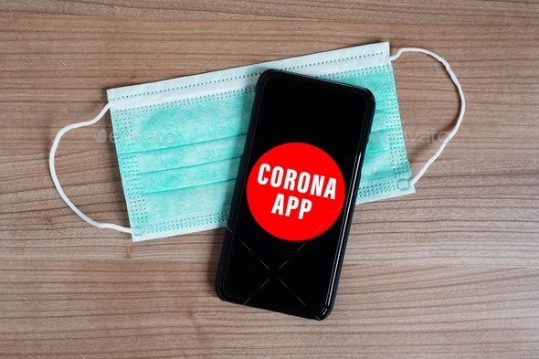 mock-up corona app on smartphone or mobile and face mask on desk