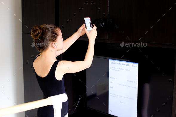 Dancer using I phone and Apple TV to stream and AirPlay online zoom dance classes google meet video  - Stock Photo - Images