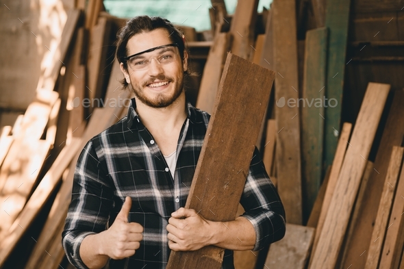 Portrait of Carpenter young SME furniture shop owner smiling in wood workshop look professional skil