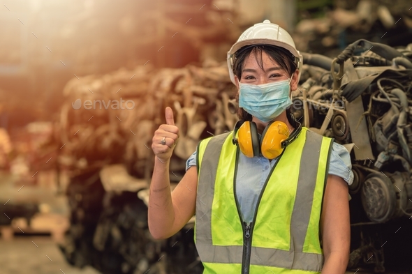Asian women worker thumbs up waring face mask happy working safety work in a heavy industrial factor
