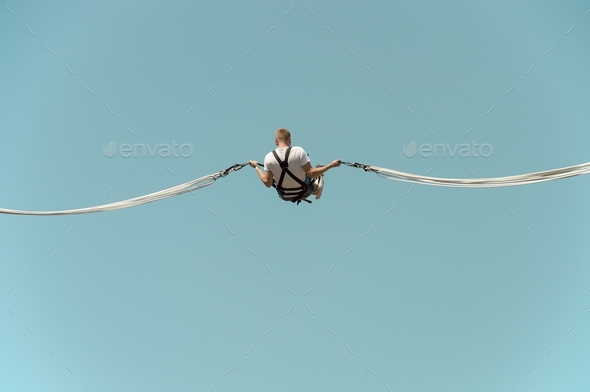 Man on blue sky background elastic rope jumping