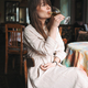 Girl with bangs drinks white wine in a cafe in a white dress - PhotoDune Item for Sale