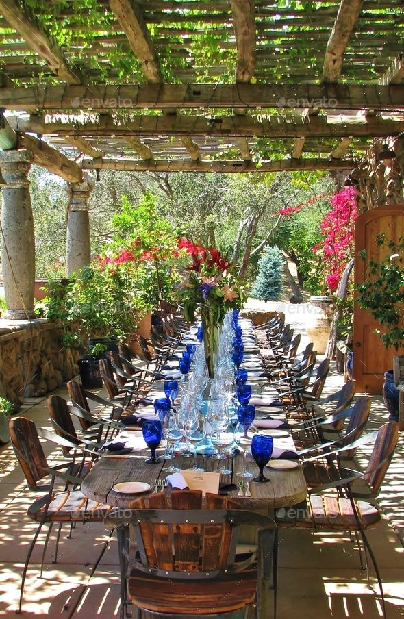 Outdoor lunch celebration with Italian blue glass, under flower ivy covered patio and rustic chairs