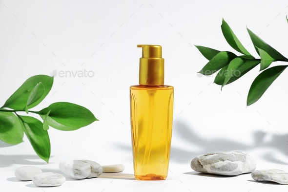 Clear bottle of yellow orange oil for sun protection, tanning or hair. White background