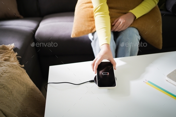 Charging mobile phone battery with wireless charging device in the table. Smartphone charging