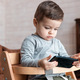 A toddler boy using mobile phone and sits on kids chair in a light vintage room. Kids and technology - PhotoDune Item for Sale