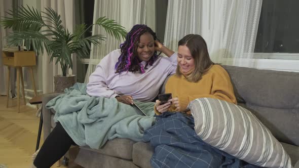 Friends African-American and European Young Stylish Women of Different Nationalities Look At photos alt