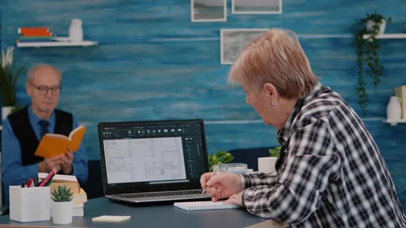 Senior Woman Architect Analysing Digital Prototype with Plans From Laptop alt