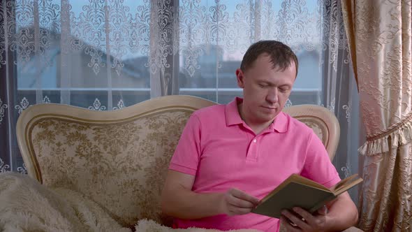 Man Reading a Book While Sitting in the Evening on the Sofa Window Background