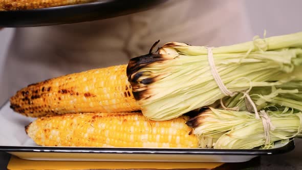 Step by step. Grilled fresh organic corn on metal tray to make  Mexican corn on the cob Elote. alt
