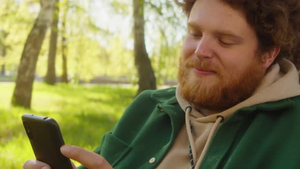 Cheerful Man Using Phone in Park alt