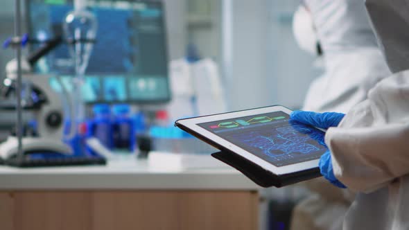 Scientist in Coverall Analyzing Virus Evolution Looking on Digital Tablet alt