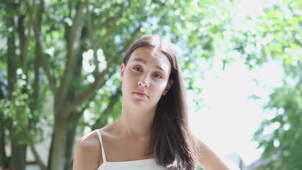 Portrait Pretty Young Brunette Female with Long Hair and White Top Green Trees alt
