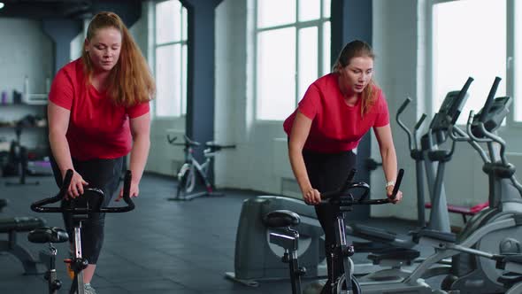 Group of Girls Performs Aerobic Training Workout Cardio Routine on Bike Simulators Cycle Training alt
