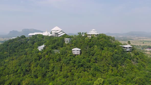 Aerial view of Thai village, hotel resort on green mountain hills with forest trees, Ratchaburi,
