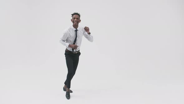Office Black Man in a Suit Dances Expressively and Smiles Against a White Background alt