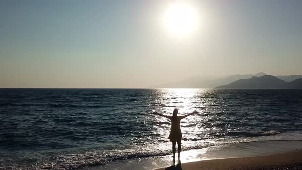 Aerial Drone Footage of a Girl Spreading Her Arms Feeling Like a Queen at a Beautiful Beach