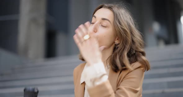 Businesswoman Taking Off Mask From Her Face During a Coffee Break Outdoors alt
