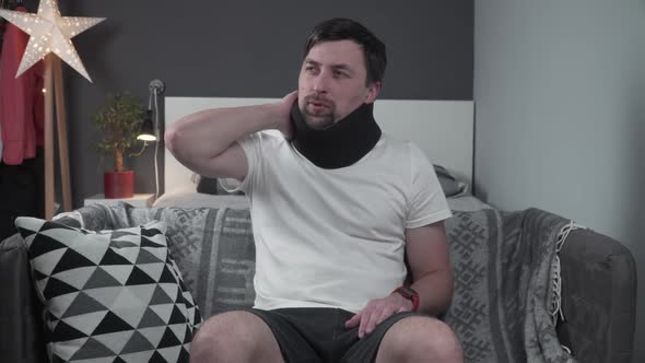 Man in Foam Collar After an Accident Suddenly Felt Sharp Pain in His Neck on Couch alt