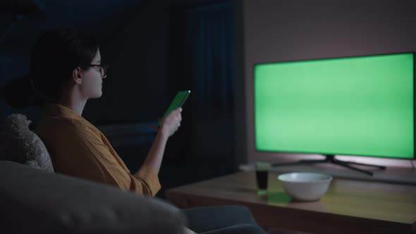 Teen Girl is Sitting on the Sofa at Home in the Evening Watching Tv and Using Phone Chroma Key