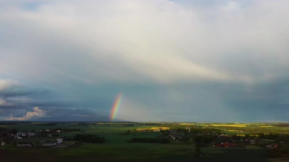 The Rainbow Over Agriculture Landscape Many Fields of Yellow Rapeseed Aerial View 4K alt