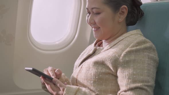 Asian female passenger sitting at seat using mobile phone