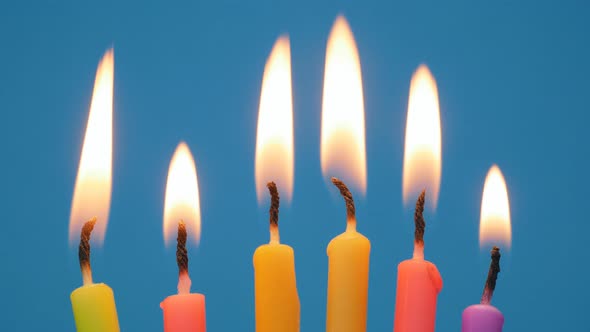 Lighted Candles in a Birthday Cake on a Blue Background alt