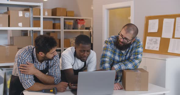Diverse Small Business Owners Discuss Idea on Laptop in Warehouse alt