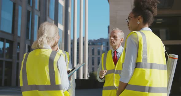 Diverse Team of Engineers Discussing Project Standing Outdoors Downtown alt