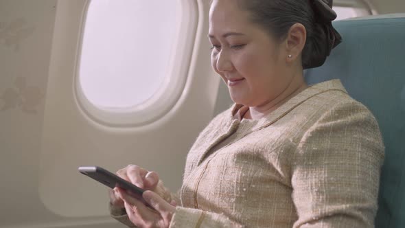 Asian female passenger sitting at seat using mobile phone