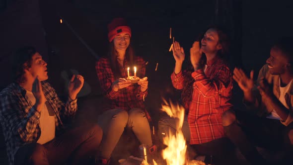 Attractive Young Woman Hiker Is Celebrating Birthday in Forest Getting Cake Blowing Candles alt
