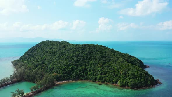Isolated tropical island with trees forest and rocky shoreline in the middle of colorful lagoon with alt
