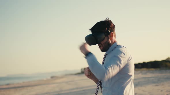 Young Business Guy Boxing in Virtual Reality with Headset at the Beach alt
