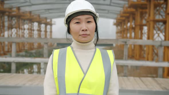 Slow Motion Portrait of Female Builder Standing Outside Construction Area Wearing Safety Helmet alt