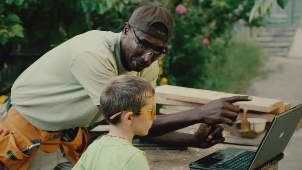 Carpenter and Boy Work with Wood Following Video Instruction