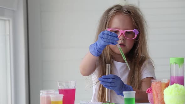 A little girl in pink glasses conducts experiments.