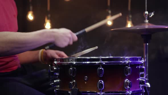 Drummer plays snare drum with sticks and dust hi-hat close up