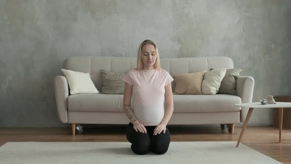 Beautiful pregnant female does yoga in morning.