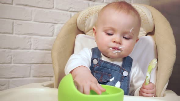 Baby Licks Her Mouth with Her Tongue Then Dips Her Fingers Into Cup of Food