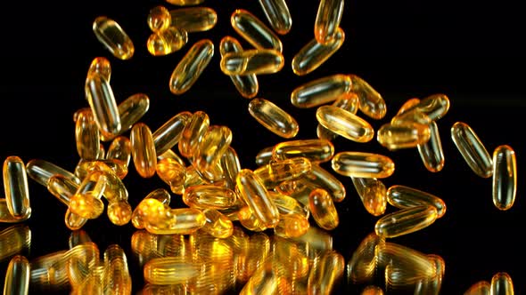 Super Slow Motion Shot of Falling Golden Capsules on Black Background at 1000Fps alt