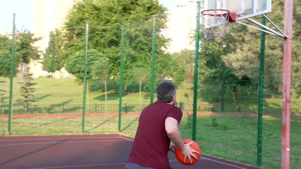 Man Playing Basketball Throwing Ball Into Basket on Playground Sport alt
