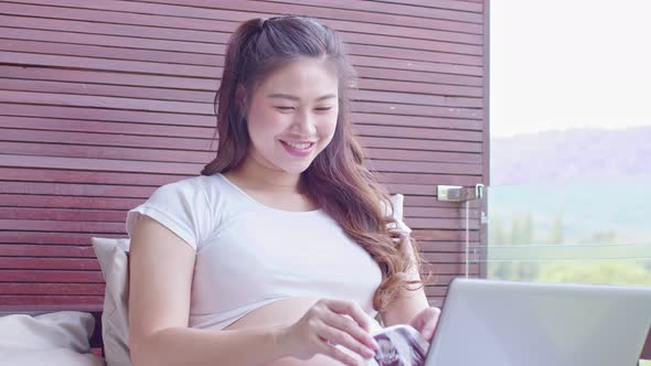 Pregnant Woman sitting on  couch video call conference on mobile phone with family alt