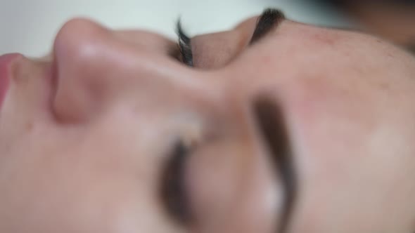 Closeup Eye of Young Slim Woman in Beauty Salon Doing Permanent Eyebrow Tattooing alt