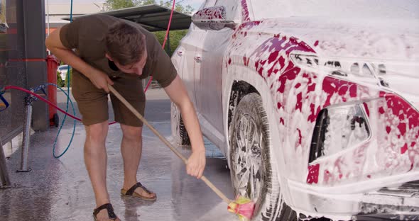 Man Washing Her Car in a Self Service Car Wash Station alt