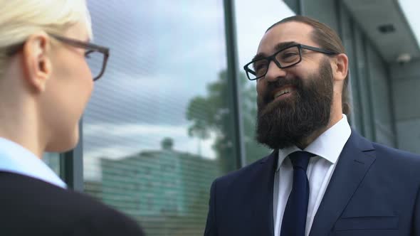 Happy Bearded Businessman Looking at Female Colleague, Discussing Successful Job