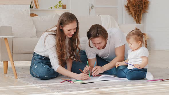 Happy Family Home Leisure Young Parents Drawing Coloring Picture with Pencils Laying on Floor alt