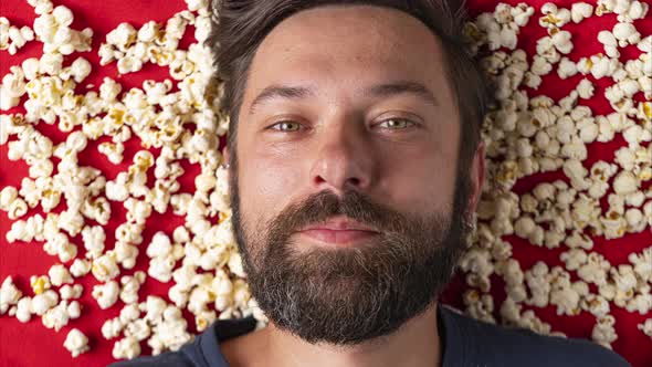 Stop Motion with a Bearded Man Eating Popcorn Flakes on a Red Background