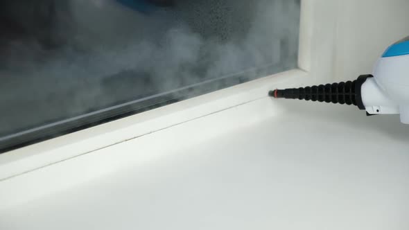 A Man Washes the Joints on Window with a Steam Cleaner